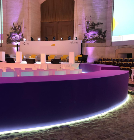 Salle moderne avec une scène éclairée, des sièges colorés et un fond décoratif.