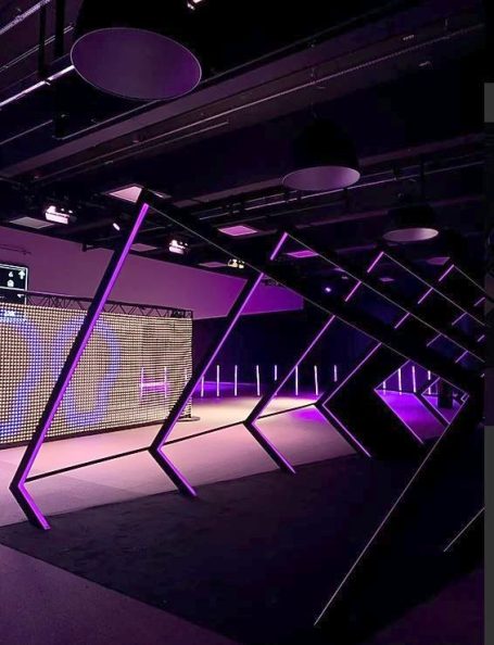 Intérieur moderne avec des structures inclinées et un éclairage violet.