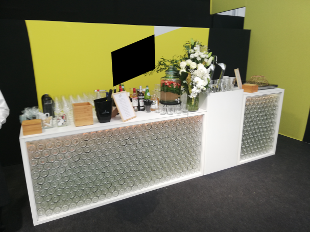 Bar avec un comptoir blanc, décoré de fleurs et d'éléments en bois, sur fond jaune.