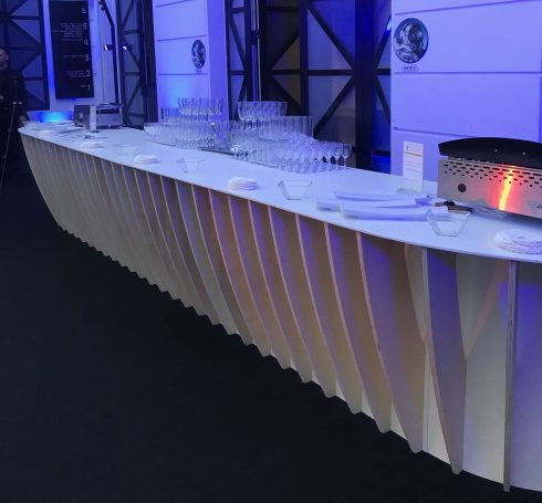 Un comptoir élégant avec des surfaces ondulées, éclairé par des lumières bleues.